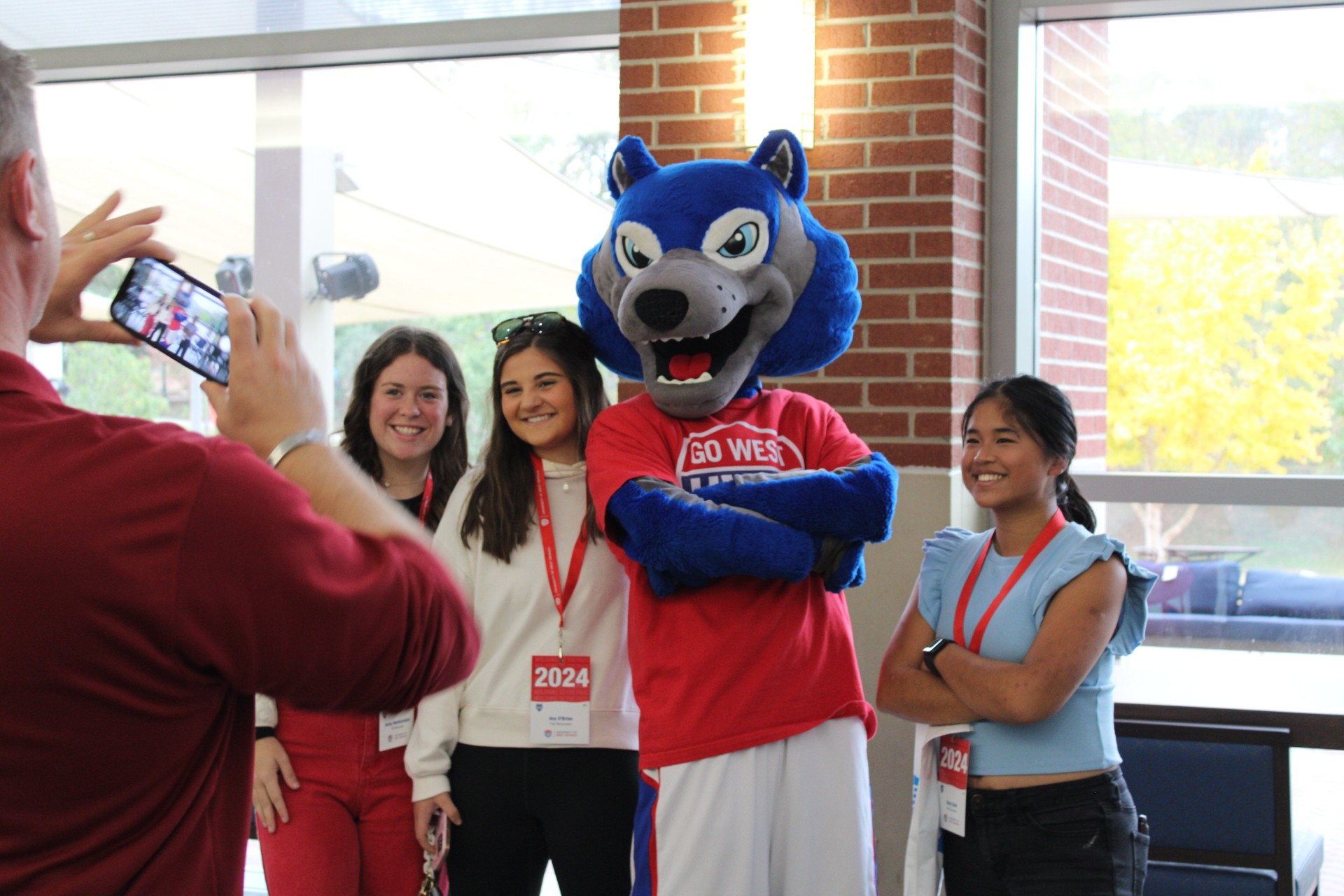 Three female students posing for a picture with Wolfie inside the Campus Center.