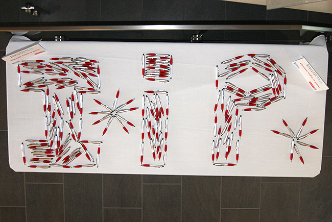 Photograph of a table of pens arranged as the letters I I P