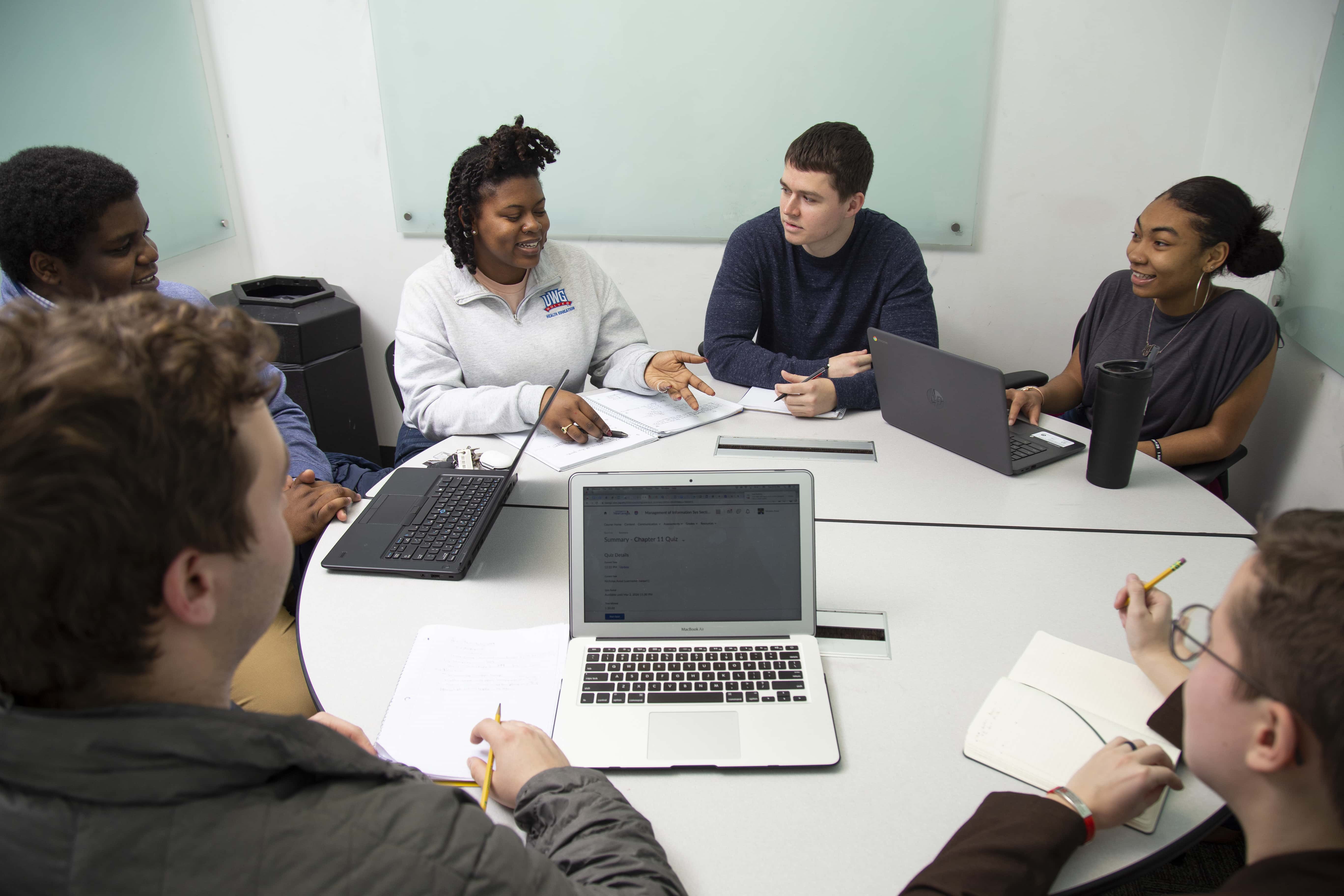 Group of students working together on their computers in a UWG study room, located in the library.