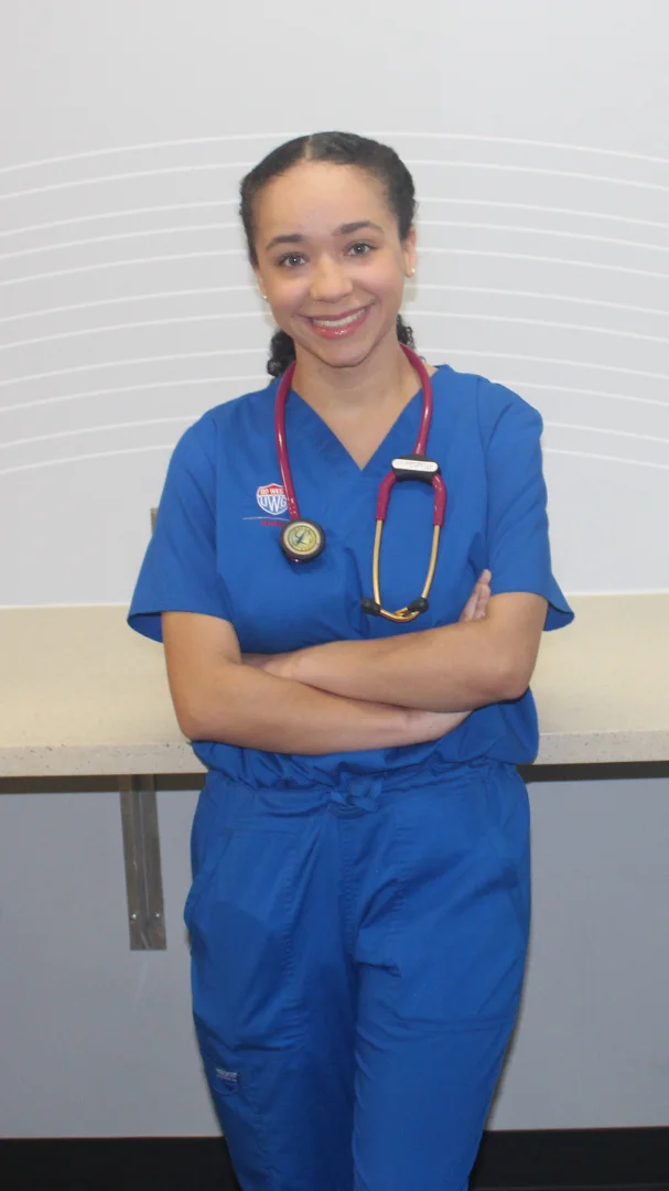 Female nursing student smiling, wearing blue UWG scrubs with a stethascope around her neck.